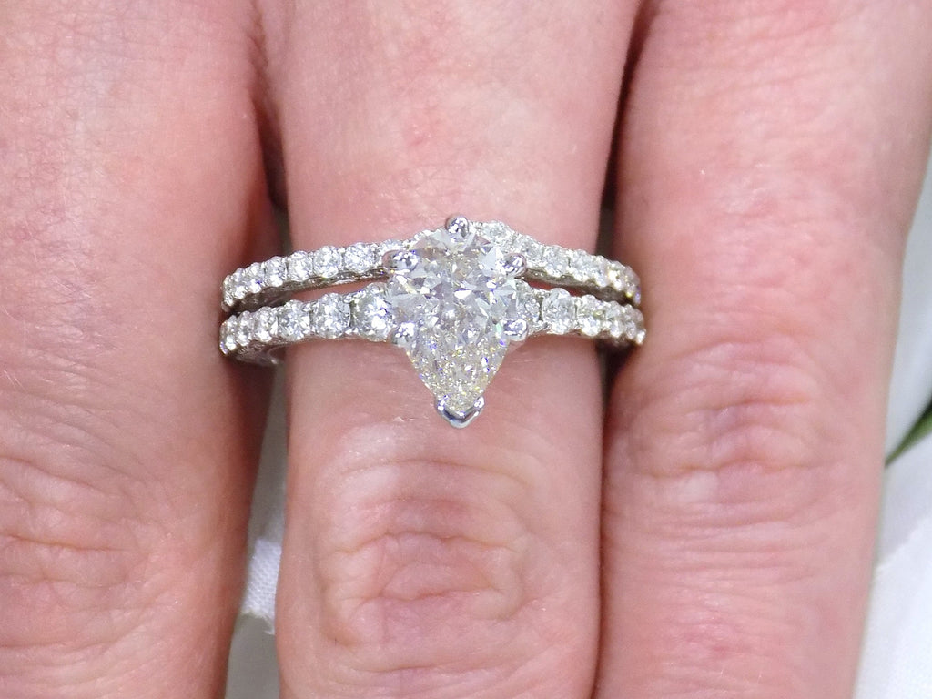 This is a women's 2-piece wedding set including the engagement ring and a matching band with a 1.51ct natural pear shape diamond center plus 1.64ct in natural diamond accents shown together on a woman's finger.