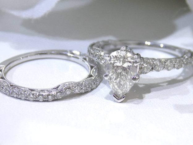 This is a women's 2-piece wedding set including the engagement ring and a matching band with a 1.51ct natural pear shape diamond center plus 1.64ct in natural diamond accents shown side by side on white background.