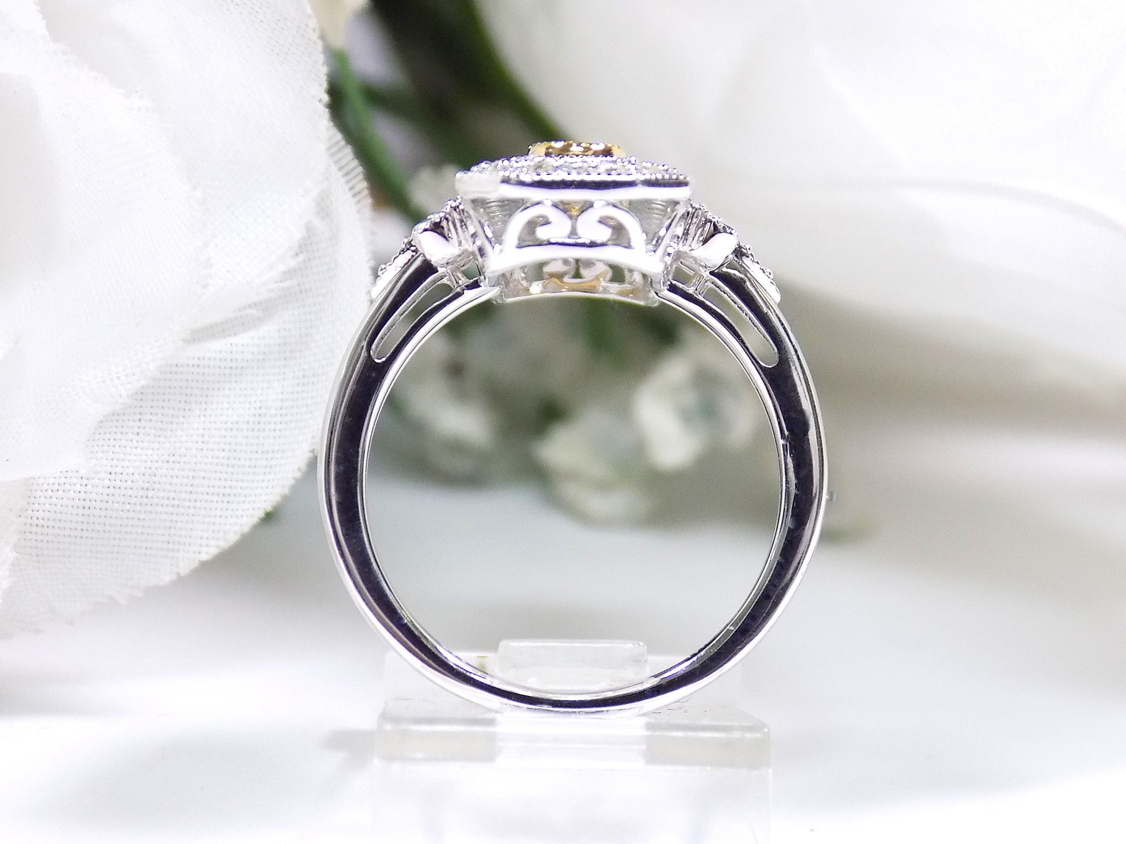 This ring is a filigree style natural diamond ring with a total of .37ct natural diamonds in 2-tone white and yellow gold on a white floral background side view.
