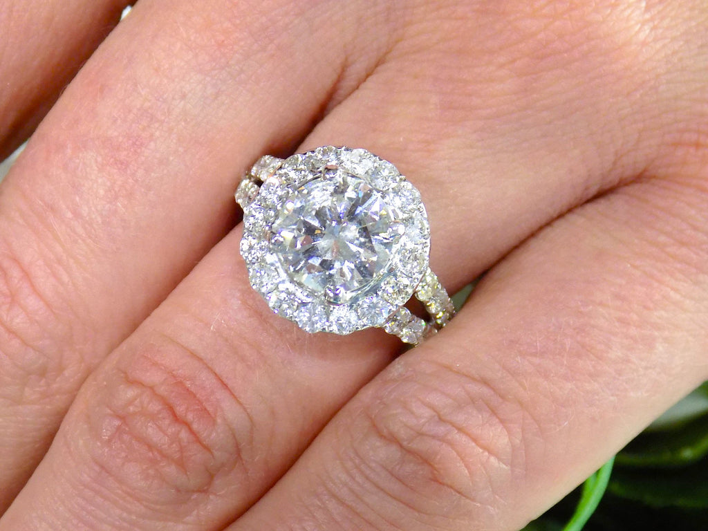 This is 3.55ct total weight natural diamond ring with a 2.05ct natural round diamond center in white gold shown on a woman's finger.