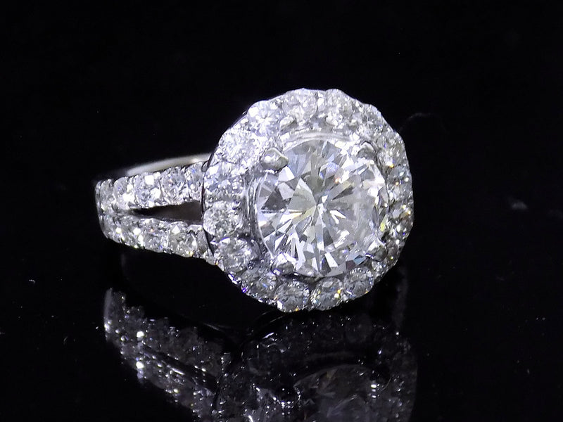 This is 3.55ct total weight natural diamond ring with a 2.05ct natural round diamond center in white gold shown on a mirrored black background.