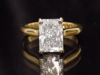 This is a 3.01ct Natural radiant cut diamond solitaire in yellow gold with a dark background.
