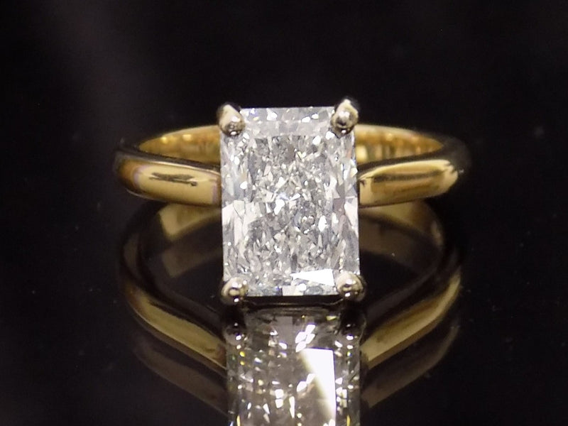 This is a 3.01ct Natural radiant cut diamond solitaire in yellow gold with a dark background.