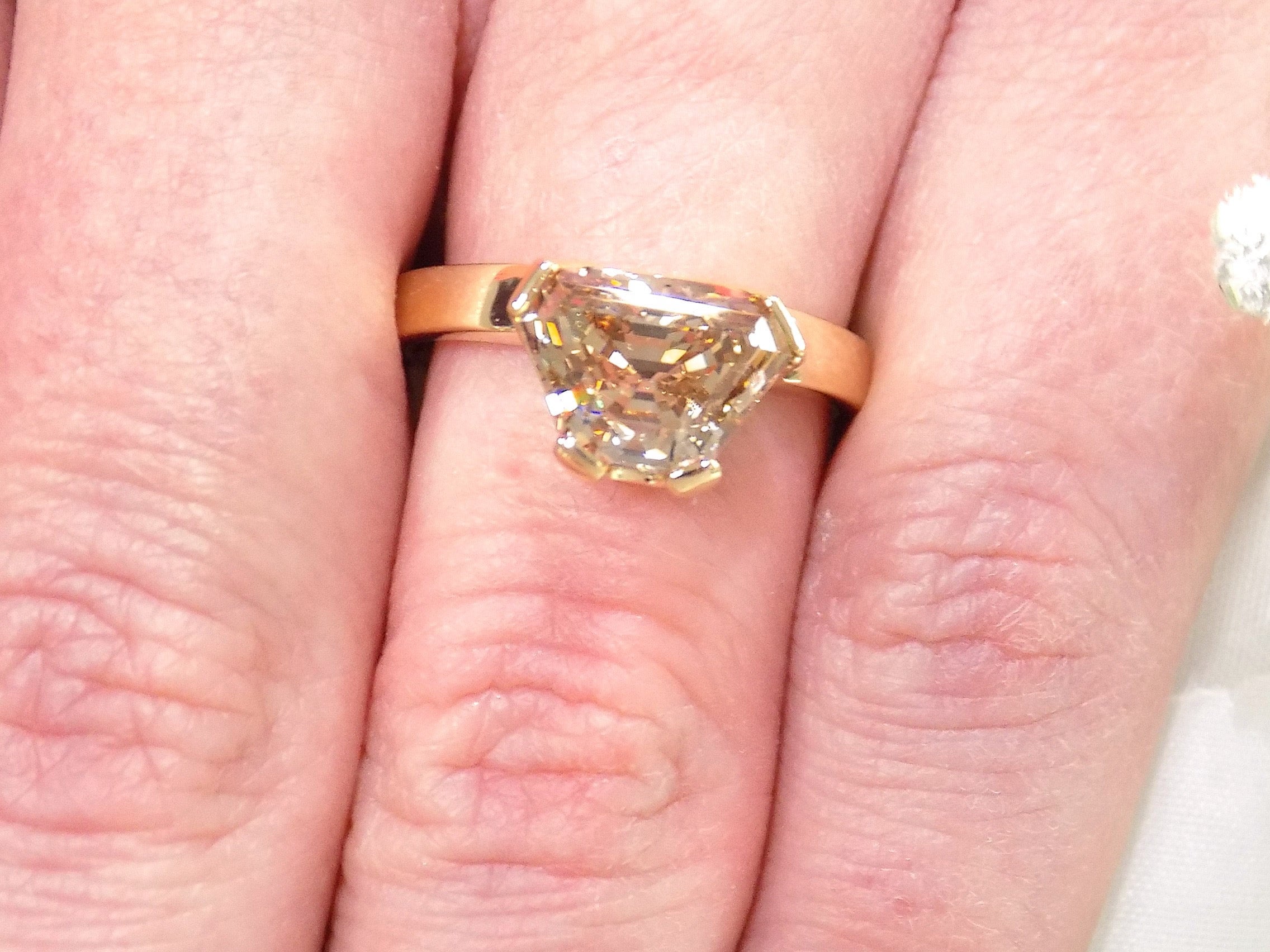 This is a 3.06ct natural GIA certified custom shield cut fancy chocolate diamond solitaire ring in yellow gold shown on a woman's finger.