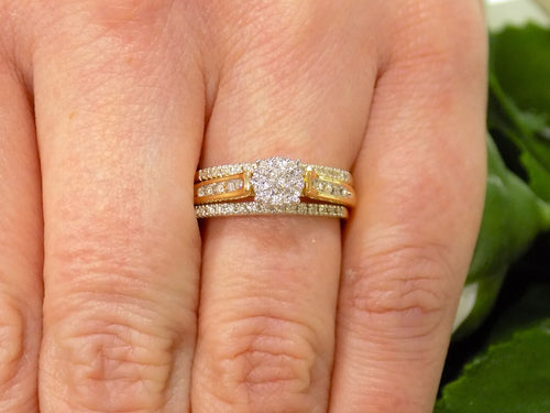 This is a halo style 2-piece diamond wedding set with 2 matching bands in yellow gold shown on a woman's finger.