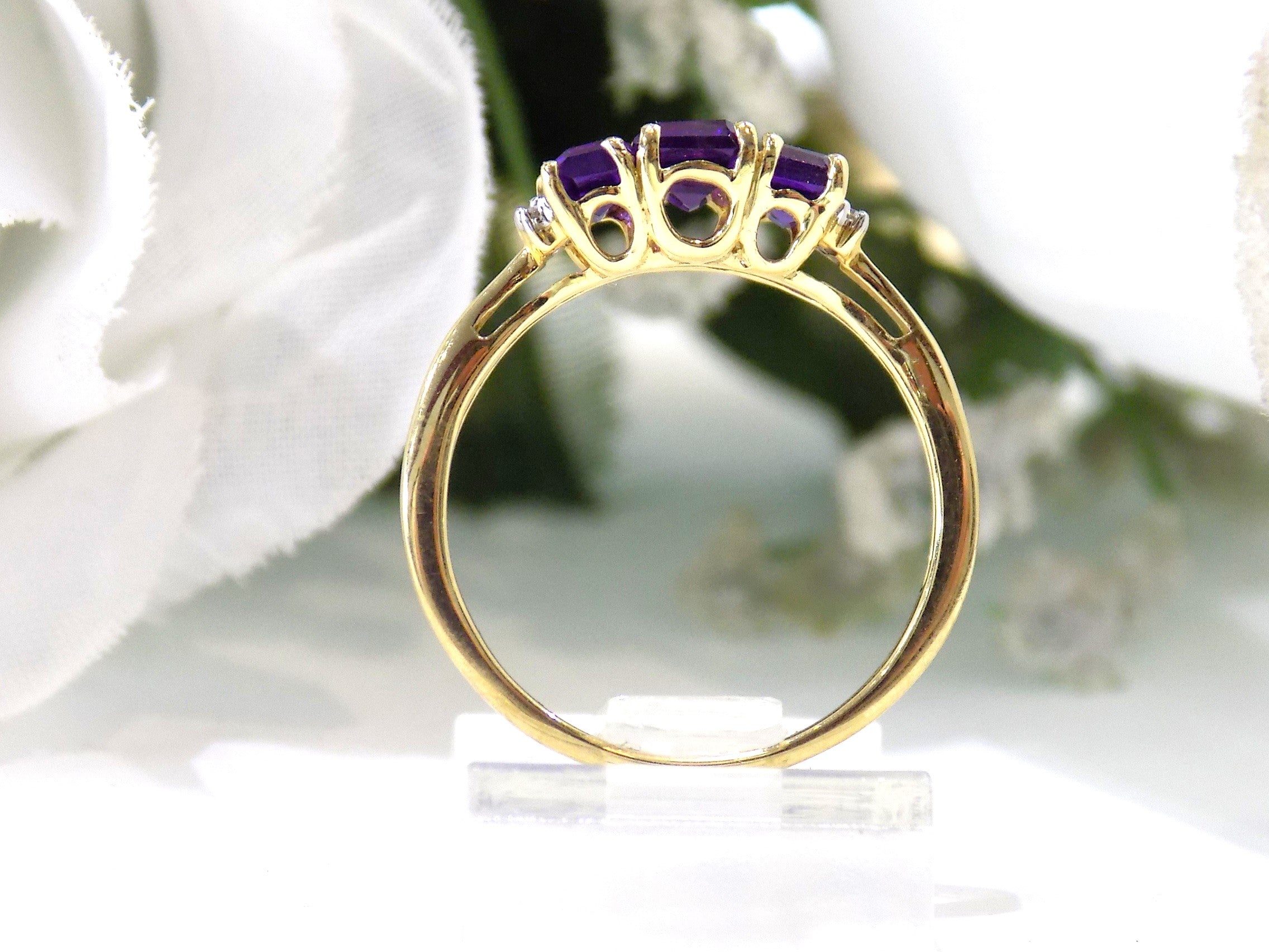 This is a 1.25ct total weight 3-stone natural amethyst and round diamond  ring in 10K yellow gold side view with a white background.