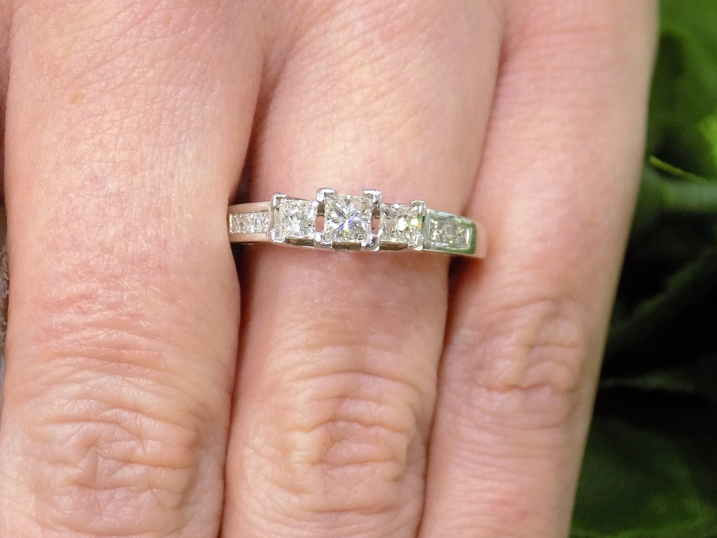 This is 3-Stone style .75ct total weight natural princess cut diamond ring in white gold shown on a woman's finger.