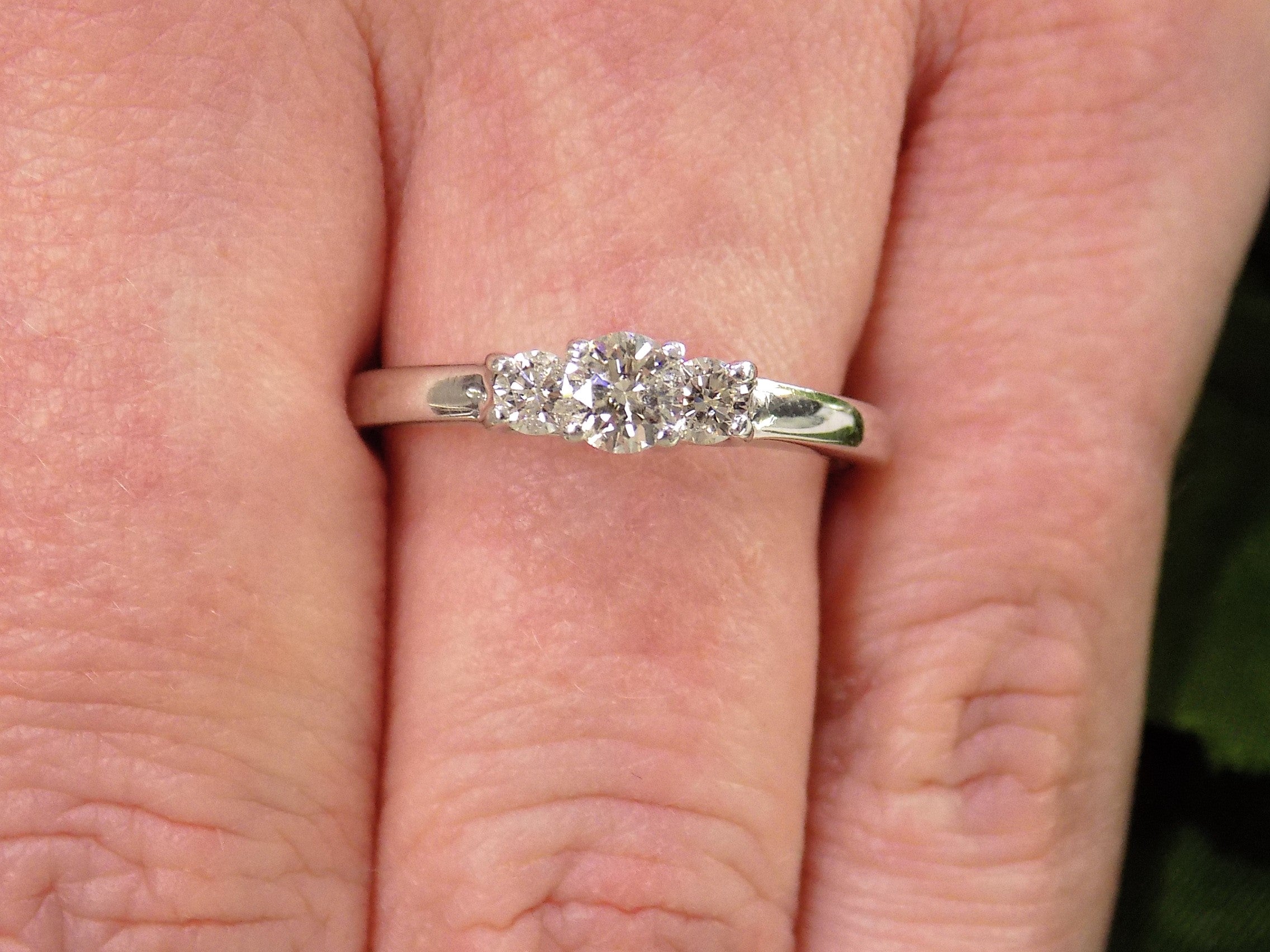 3-Stone natural diamond ring in white gold on a woman's finger.