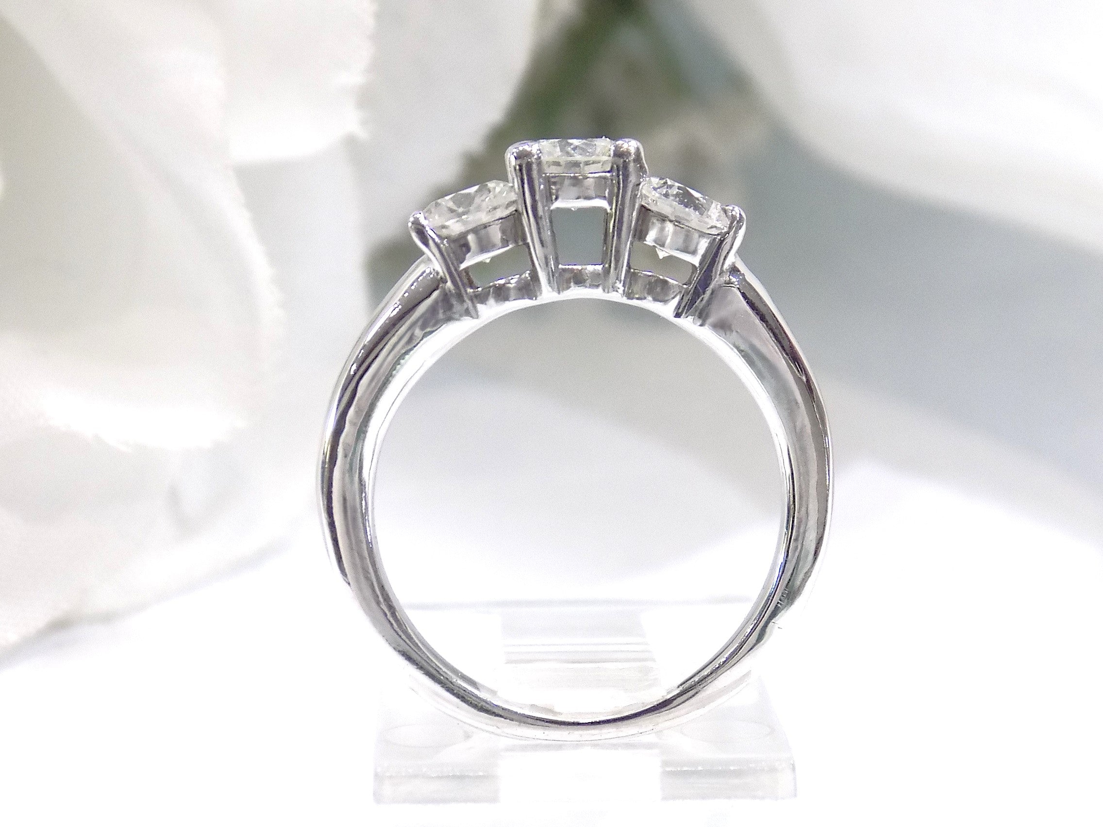 This is a side view 3-stone style natural .90ct total weight round diamond ring in white gold with a white background.