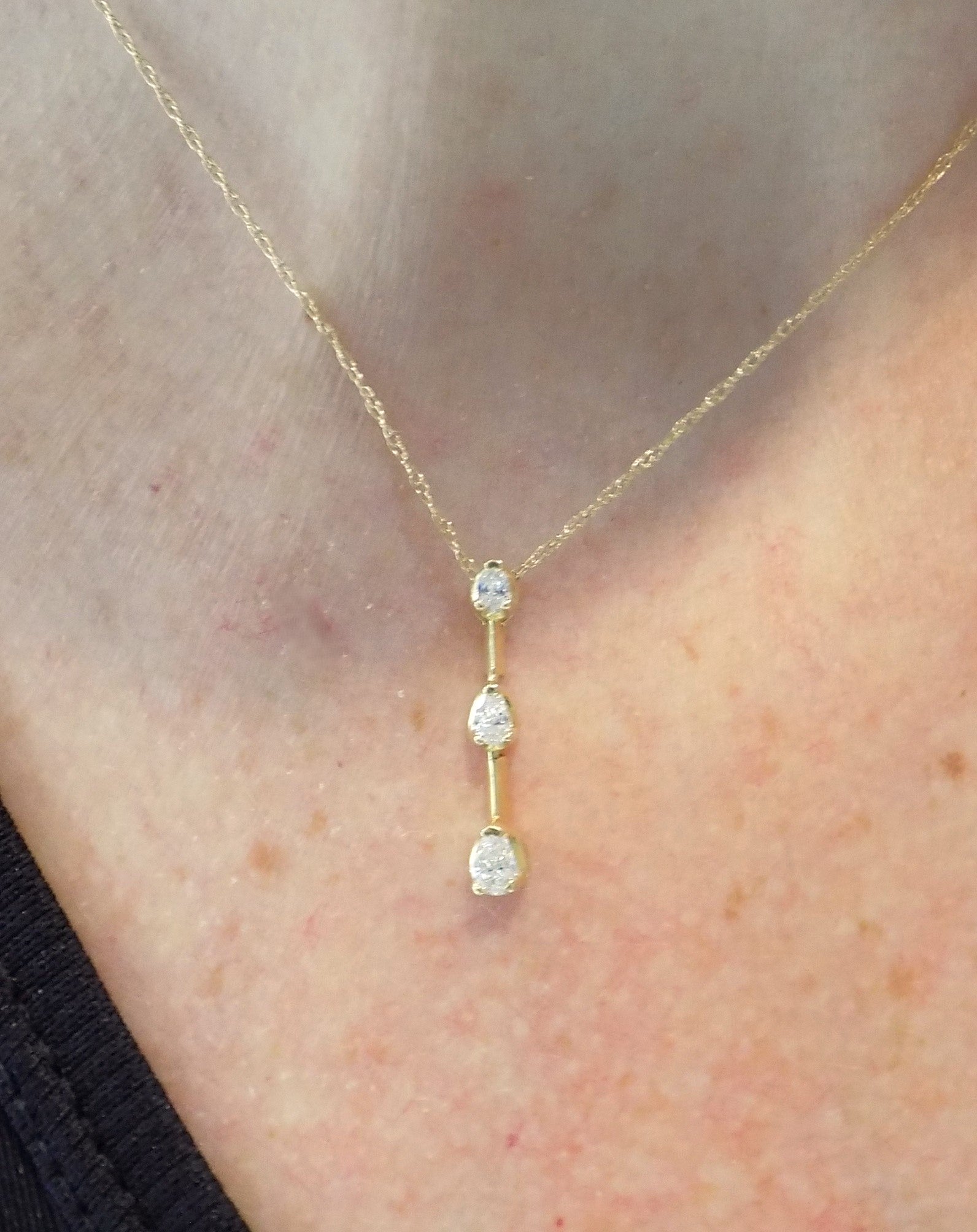 This is a vintage 3 stone necklace with .20ct total weight natural pear shape diamonds with a 14K yellow gold chain on a ladies neck.