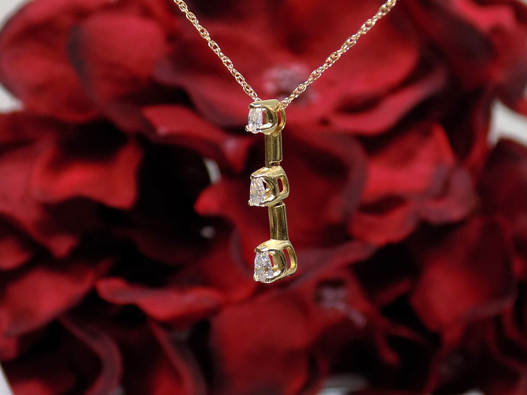 This is a side view of a vintage 3 stone necklace with .20ct total weight natural pear shape diamonds with a 14K yellow gold chain. 