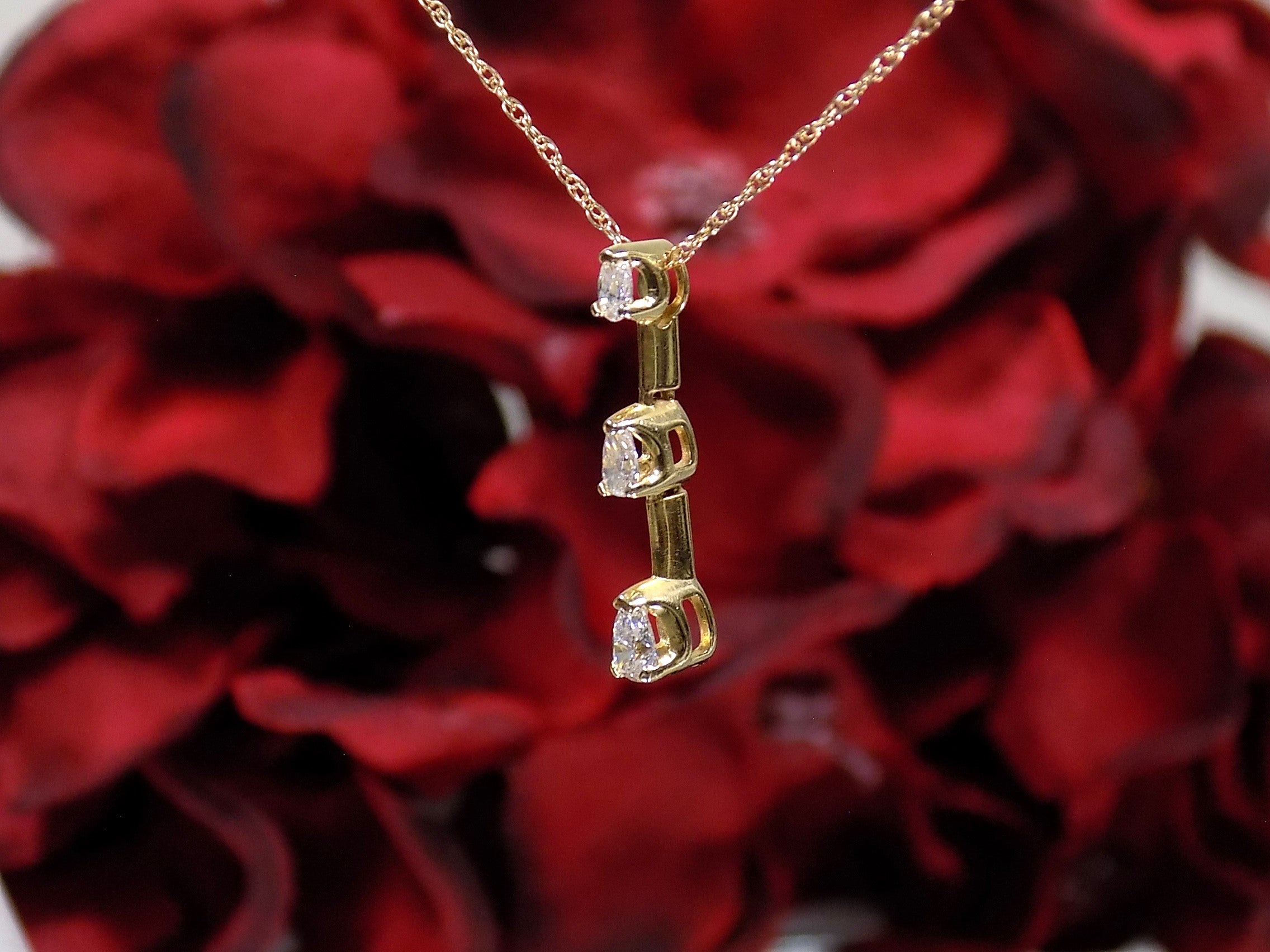 This is a side view of a vintage 3 stone necklace with .20ct total weight natural pear shape diamonds with a 14K yellow gold chain. 