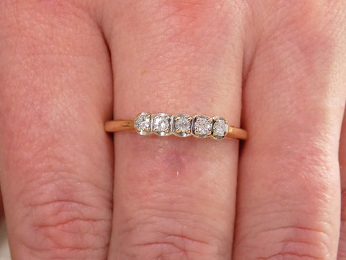 Preowned or estate small 5-stone natural diamond band in yellow shown on a woman's finger.