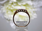 This is a side view of a preowned or estate small 5-stone natural diamond band in yellow gold with a flowery background.