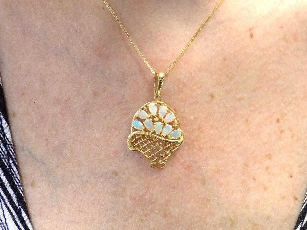 The is a genuine oval shape opal basket pendant in yellow gold from our estate collection in like new condition shown on woman's neck.