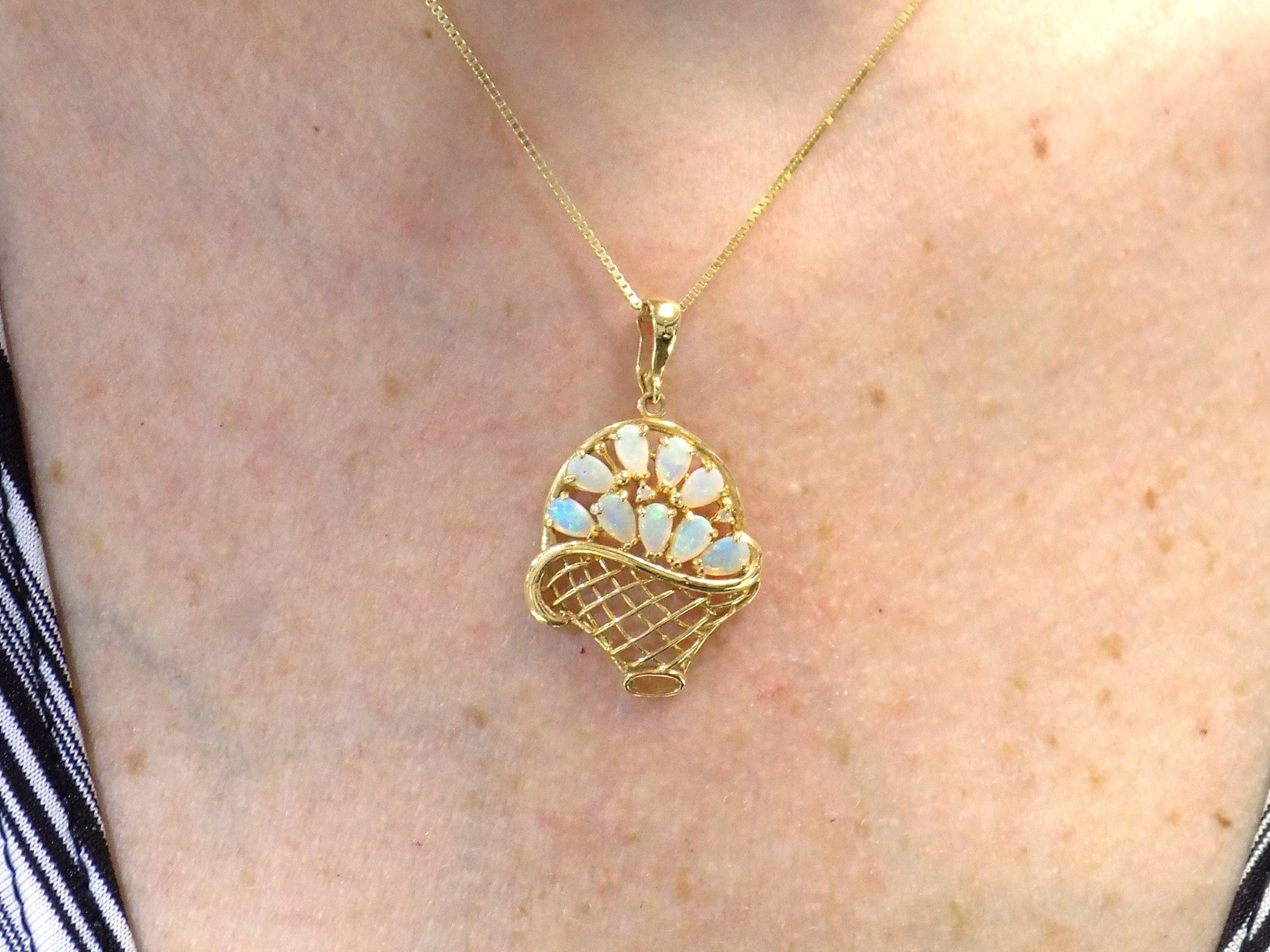The is a genuine oval shape opal basket pendant in yellow gold from our estate collection in like new condition shown on woman's neck.