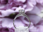 This a side view of an antique women's solitaire ring from the 1880's with natural old mine cut center shown with a floral background.