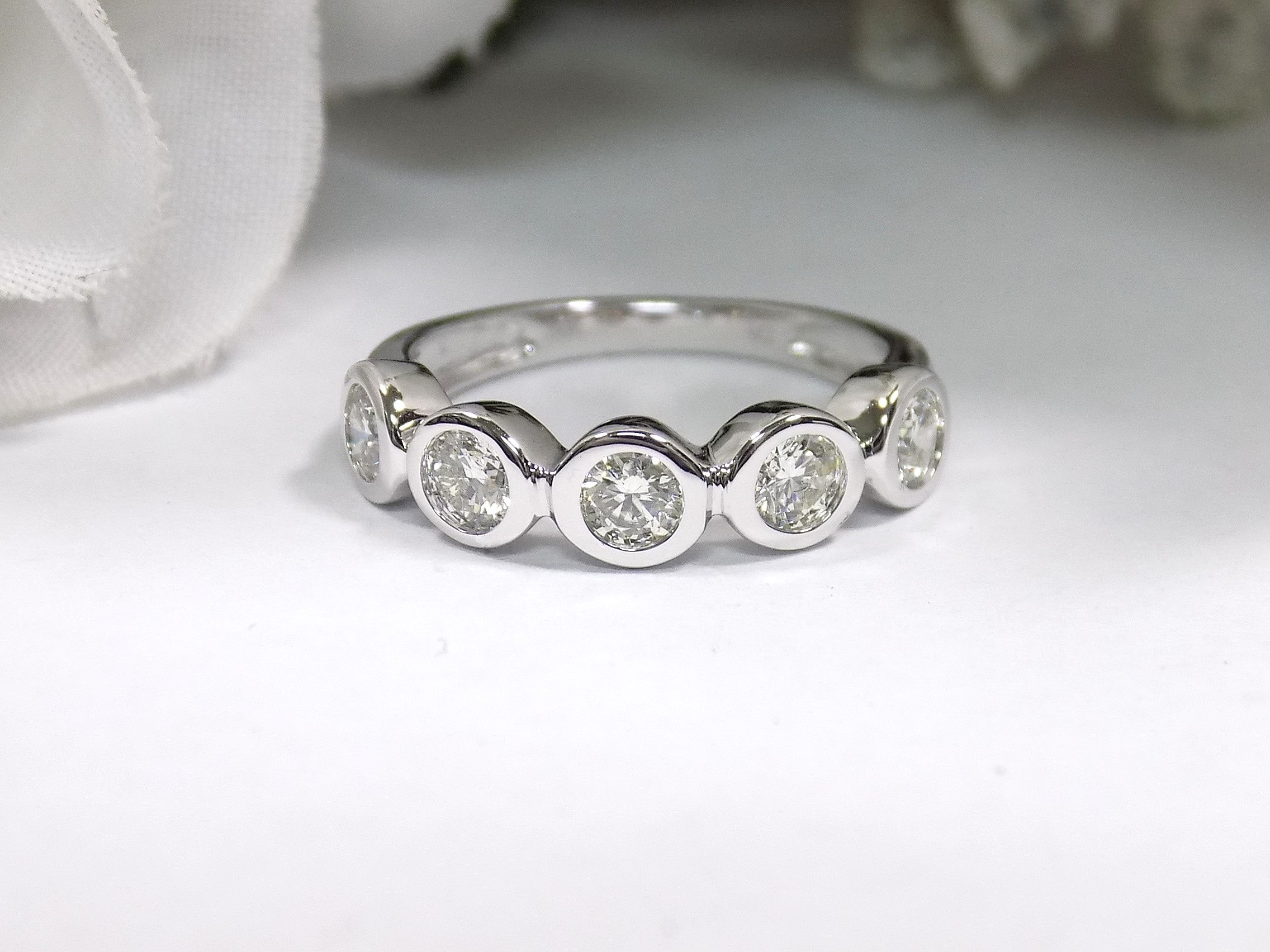 This is a 5 stone bezel set natural round diamond band in 14K white gold with a white background.