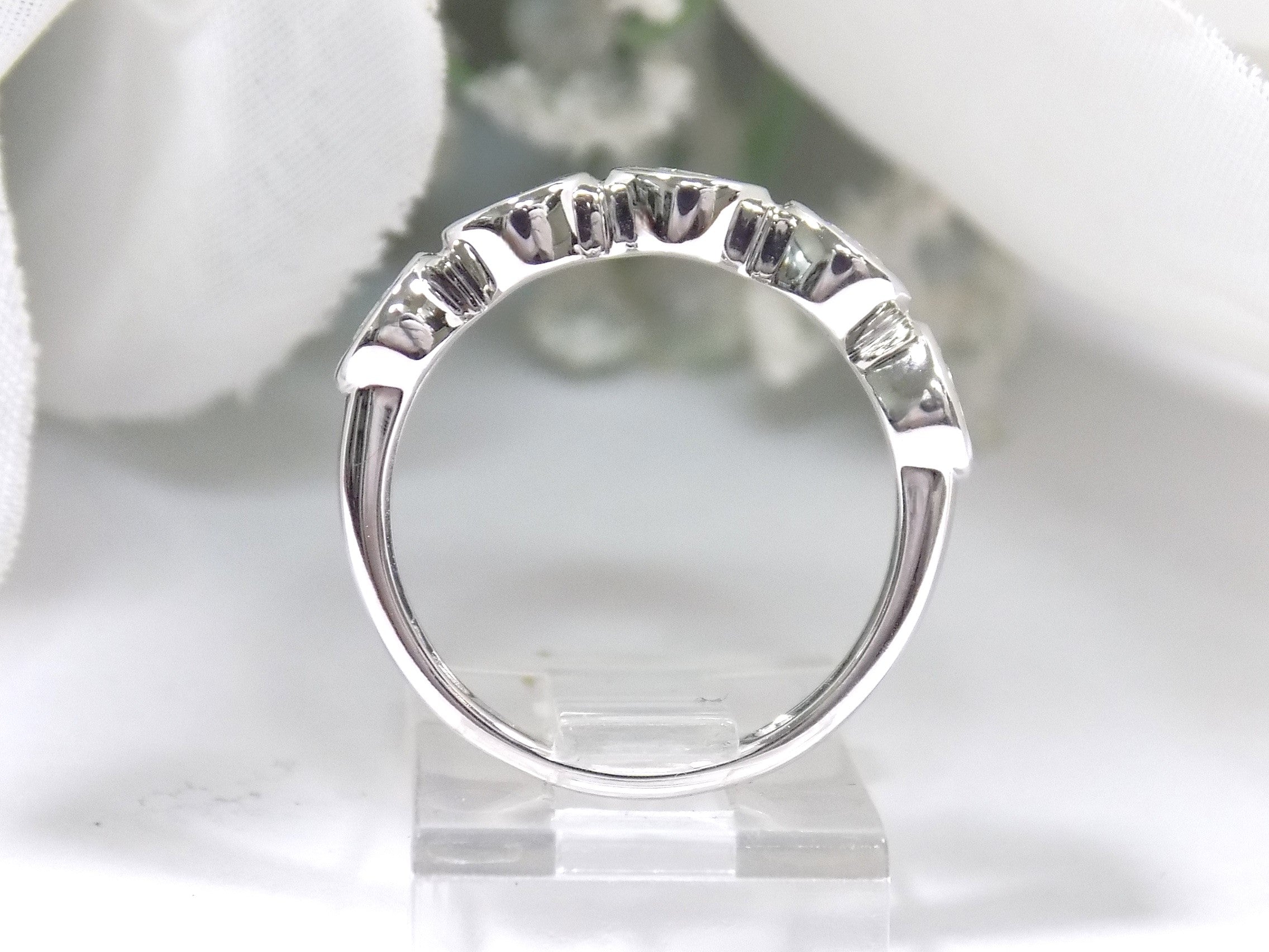 This is a 5 stone bezel set natural round diamond band in 14K white gold with a white background side view.