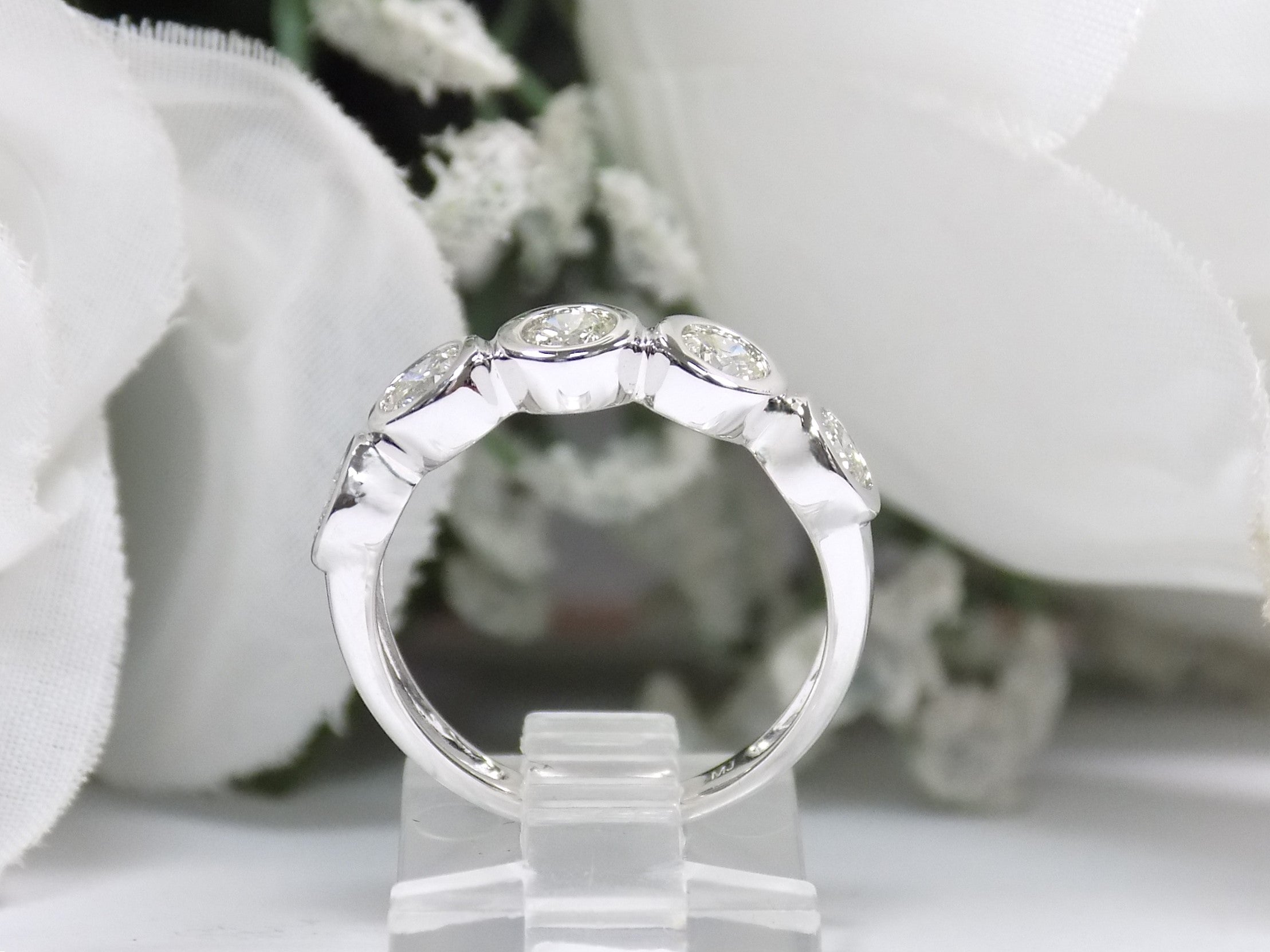 This is a 5 stone bezel set natural round diamond band in 14K white gold with a white background side view.