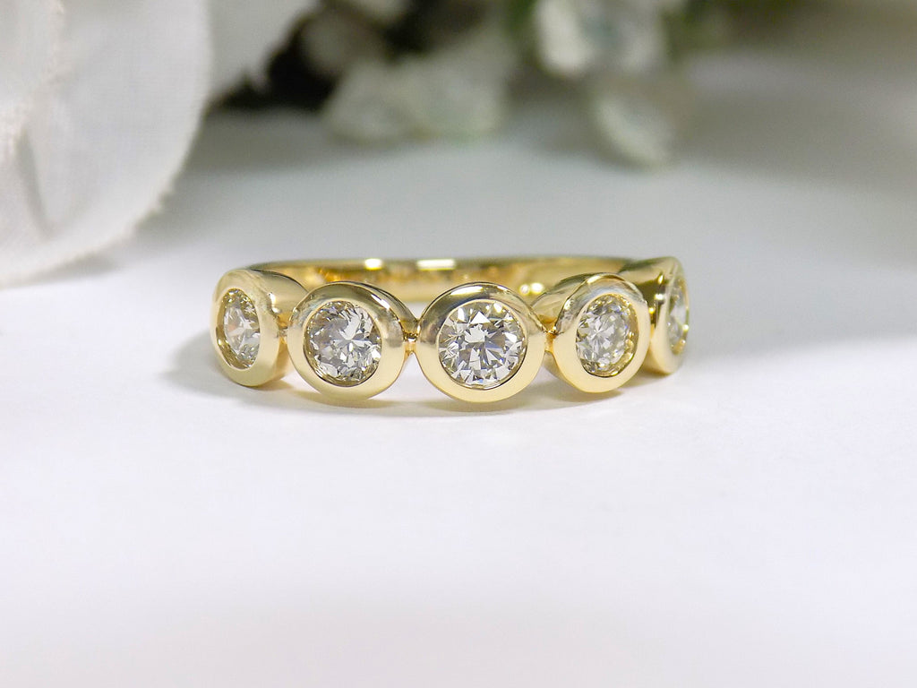 This is a 5 stone bezel set natural round diamond band in 14K yellow gold with a white background.