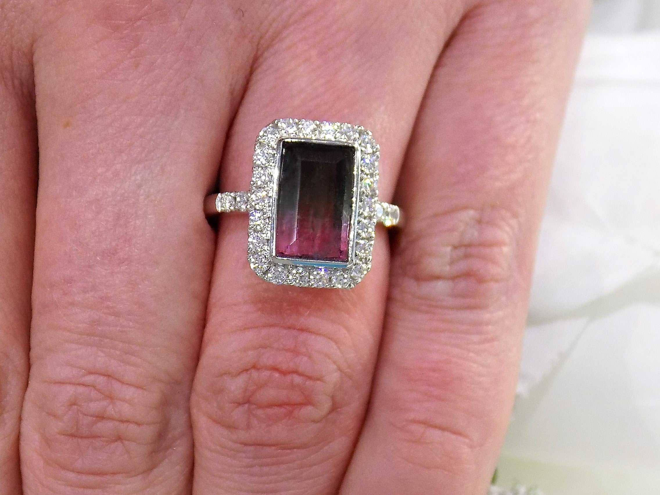 This is a women's ring with a natural 2.66ct bi-color tourmaline.  It's colors are a deep rich blueish green on one end that turns to a vivid pink on the other side.  The tourmaline is surrounded by .66ct in natural round accent diamonds in 14K white gold on a women's finger.