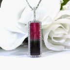 This is a women's 18ct total weight bi-color or watermelon tourmaline and diamond pendant in white gold shown with white flowery background.