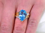This is genuine 7ct pear shape blue topaz ring in yellow gold from our estate collection in like new condition shown on woman's finger