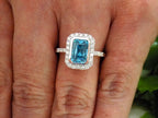 This is a women's ring has a 3.35ct natural emerald cut blue zircon in the center with .49ct natural round diamond accent's on a women's finger.