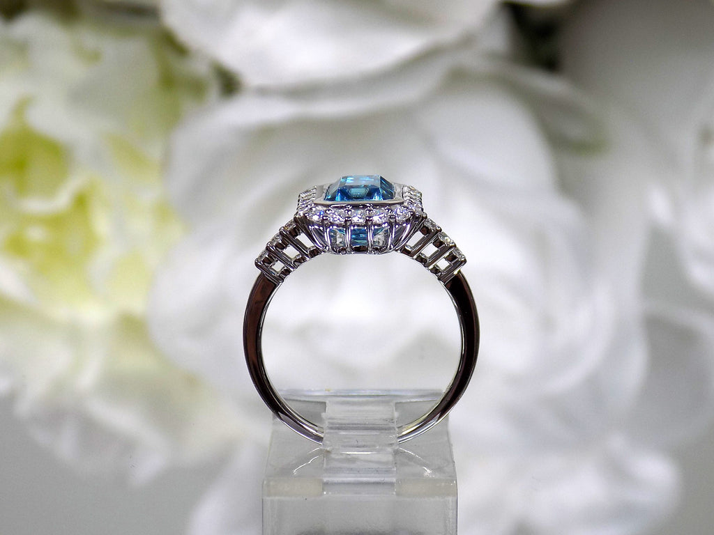 This is a women's ring has a 3.35ct natural emerald cut blue zircon in the center with .49ct natural round diamond accent's on white background side.