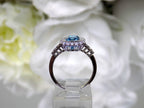 This is a women's ring has a 3.35ct natural emerald cut blue zircon in the center with .49ct natural round diamond accent's on white background side.
