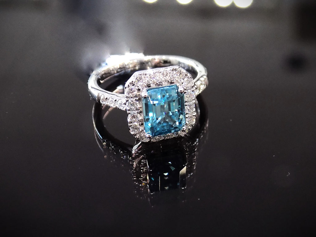 This is a women's ring has a 3.35ct natural emerald cut blue zircon in the center with .49ct natural round diamond accent's on a black background.