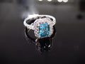 This is a women's ring has a 3.35ct natural emerald cut blue zircon in the center with .49ct natural round diamond accent's on a black background.