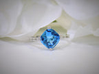 This is a diagonally set natural 2.50ct cushion cut blue topaz and .10ct diamond accents in 10K white gold with a white background
