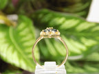 This is an estate natural marquise shaped London blue and diamond heart shape ring in 10K yellow gold side view on a mirrored surface with a green leaf background.