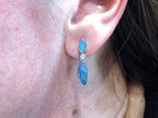 This is a women's high quality boulder opal dangle earrings bezel set in 14K white gold with diamonds for a total weight of 1.50ct in a women's ear.