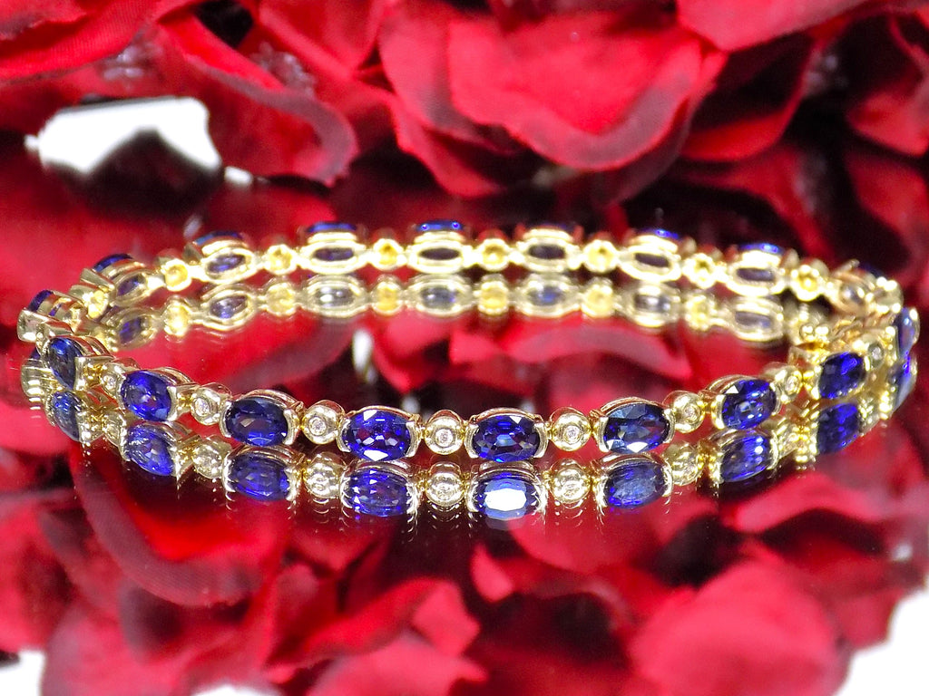 This is a women's bracelet with 10.00ct of natural oval shaped sapphires and round diamonds in 14K yellow gold on a mirrored surface with a red floral background.