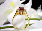This is a side view of a women's 1.46ct total natural GIA certified oval shape Burmese Ruby and diamond ring in 18K yellow gold shown with a white and green background. 
