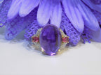 This is a women's natural 11.00ct cabochon shape amethyst with .20ct total weight natural pink tourmalines on either side plus .16ct total weight natural diamond accents on either side in 10K yellow gold with a purple floral background.