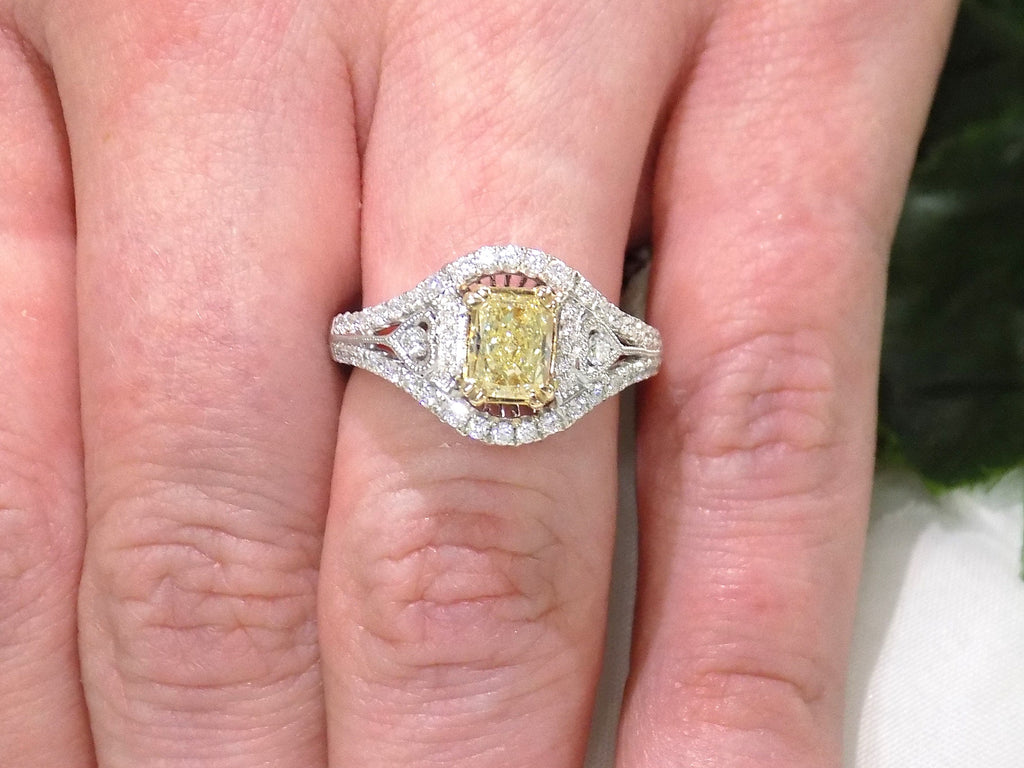 This is a 1.35ct total weight natural fancy yellow not enhanced diamond ring with white diamond accents in white gold shown on a woman's finger.