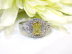 This is a 1.35ct total weight natural fancy yellow not enhanced diamond ring with white diamond accents in white gold with white flowery background.