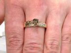 This is a very modern looking chocolate and white diamond ring in rose gold shown on a woman's finger.