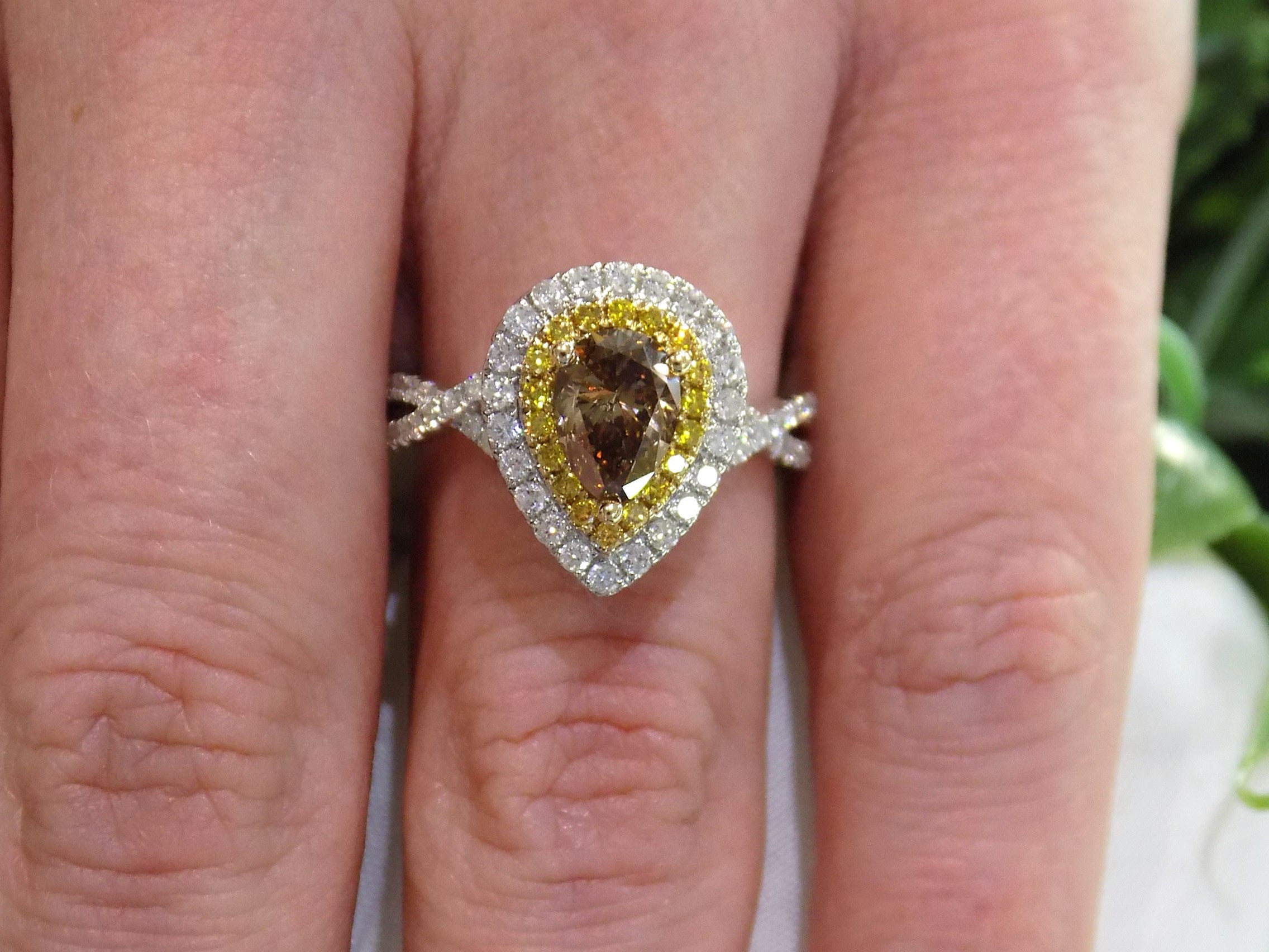 This is a 1.69ct total weight genuine natural pear shape chocolate diamond ring with canary yellow and white diamond accents in white gold shown on a woman's finger.