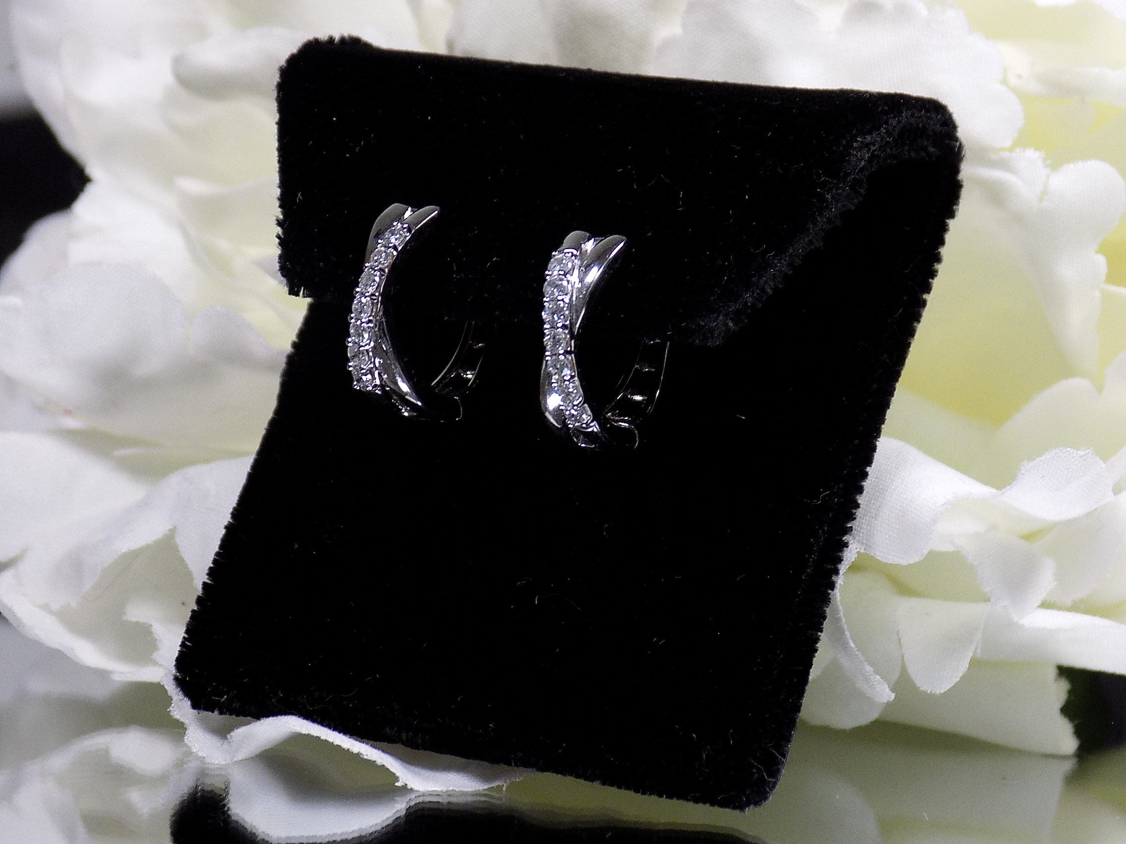This is a side view of a pair of criss-cross huggie diamond earrings in white gold.