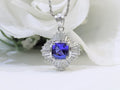 This is a women's ballerina/halo style pendant with a near perfect 2.04ct natural cushion cut tanzanite surrounded by a total weight of 1.06 natural baguette diamonds with a white floral background.