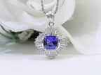 This is a women's ballerina/halo style pendant with a near perfect 2.04ct natural cushion cut tanzanite surrounded by a total weight of 1.06 natural baguette diamonds with a white floral background.