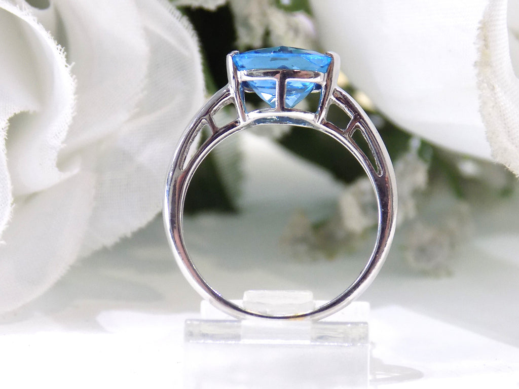 This is a tension set or channel set 4.00ct natural cushion cut blue topaz solitaire ring in 14K white gold on a white background.