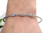 .25ct natural emerald cut and round diamond flex bracelet in 10K white gold on a ladies wrist.