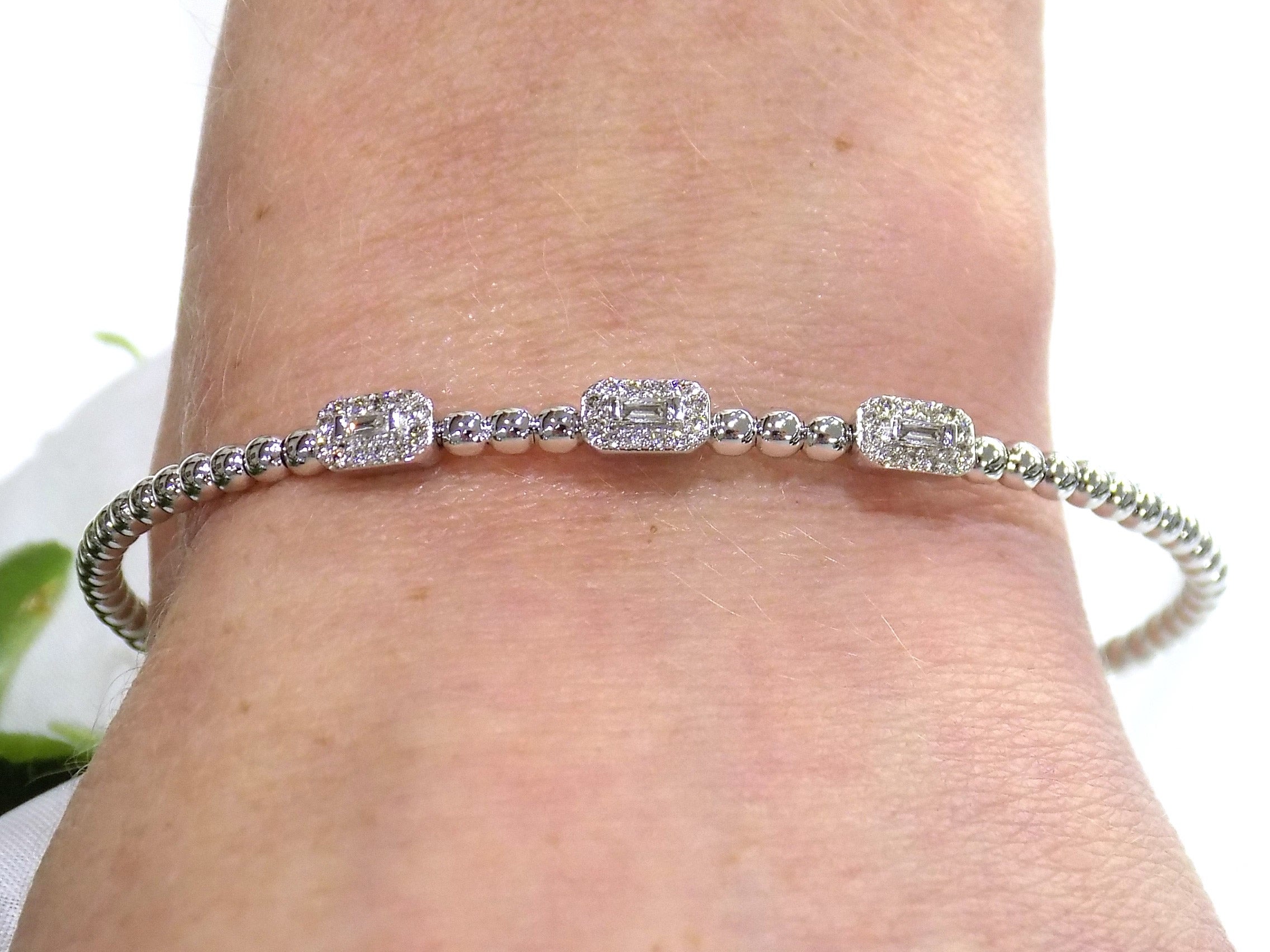 .25ct natural emerald cut and round diamond flex bracelet in 10K white gold on a ladies wrist.