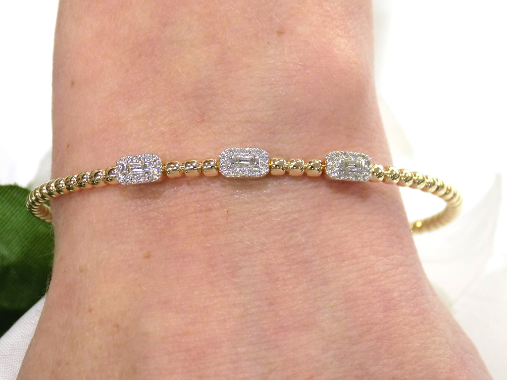 .25ct natural emerald cut and round diamond flex bracelet in 10K yellow gold on a ladies wrist.